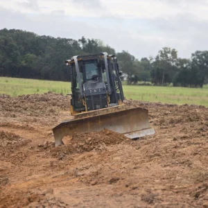 Dozer blade pushing dirt on graded ground beside a pasture in East Texas