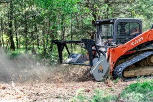 Track machine with a forestry mulcher head grinding brush in woods in East Texas